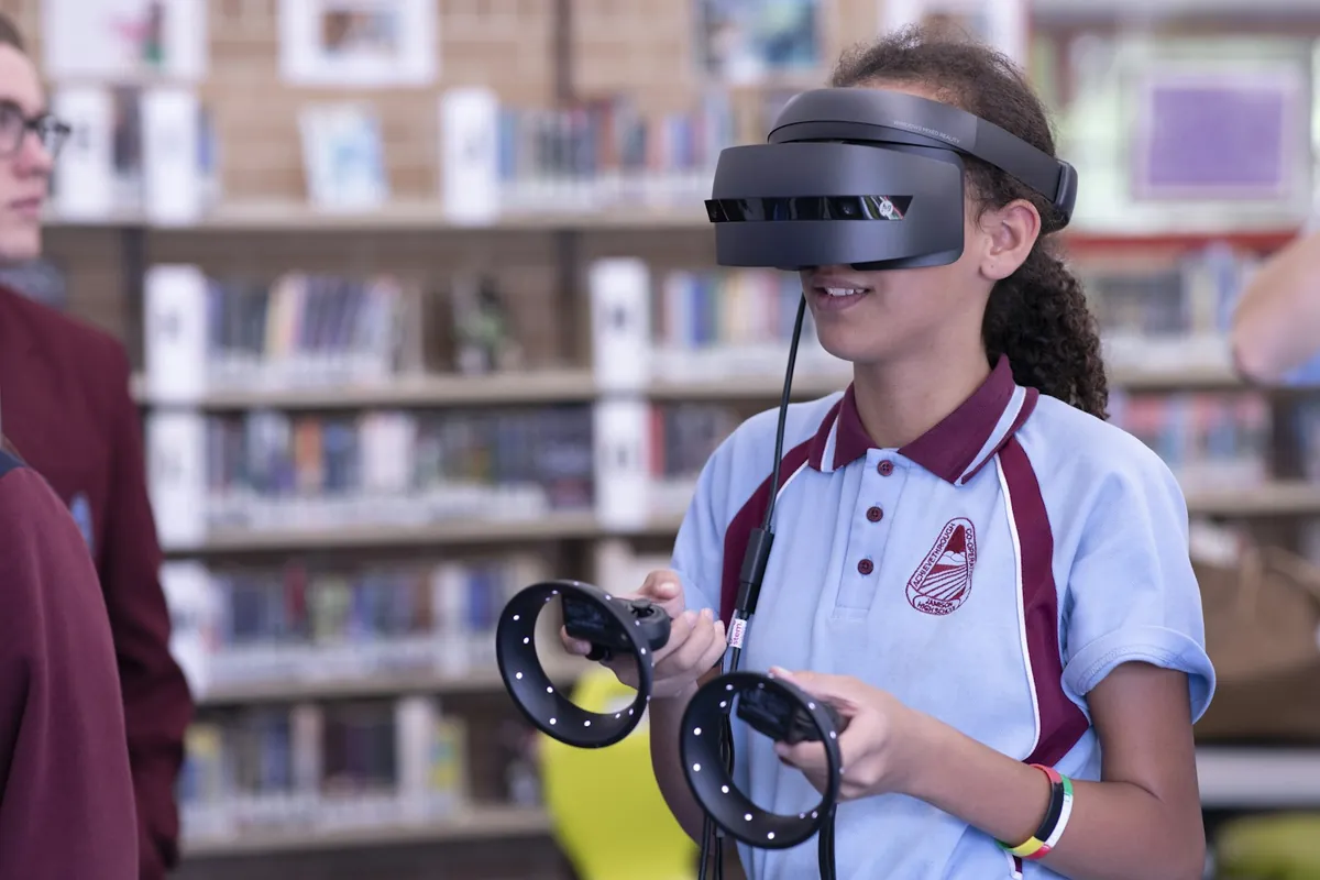 A student using a mixed reality headset and controllers in a library